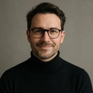 Portrait eines Mannes Anfang 40 mit Brille und schwarzem Rollkragen, freundlicher Blick in die Kamera